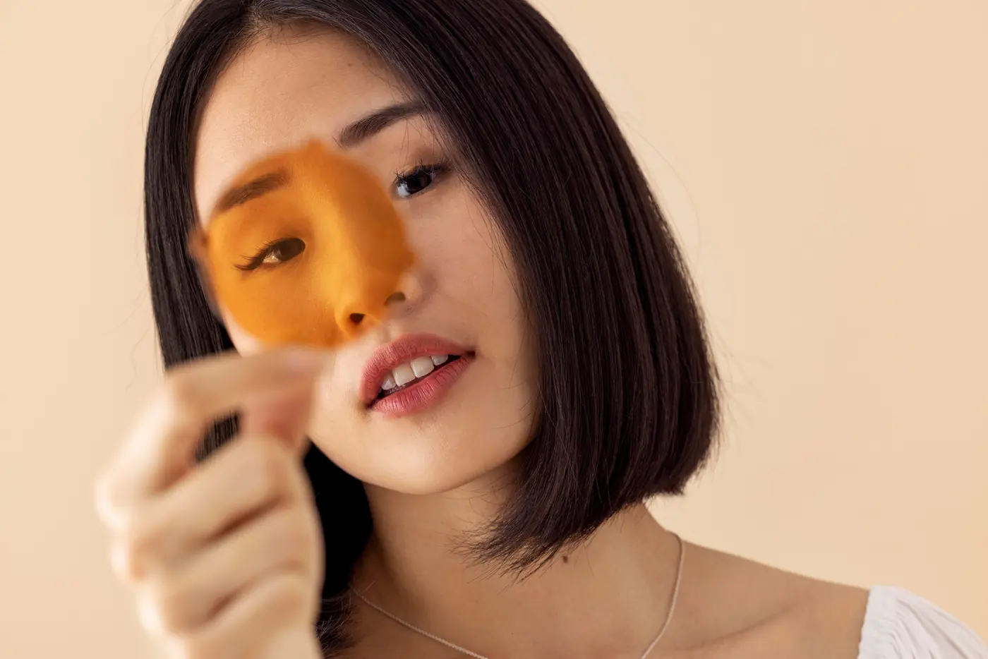 Mujer coreana sosteniendo una mascarilla facial
